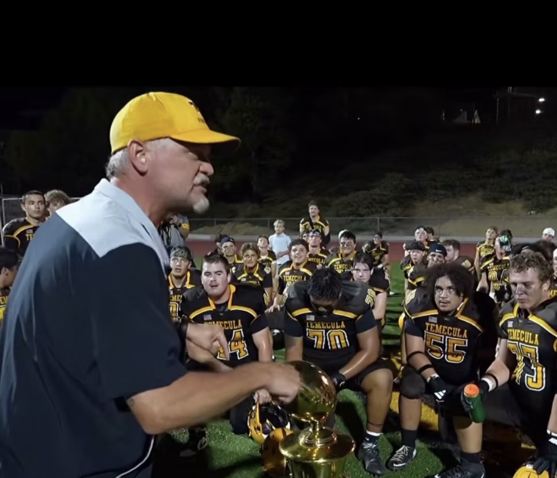 Joel Nichols speaking to Temecula Valley players gathered on the field