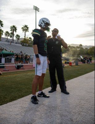 Justin J. Schaeffer Jr. in his Lakeside football uniform standing beside an adult on the sidelines