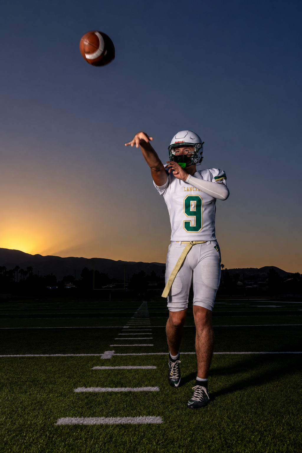 Justin J. Schaeffer Jr. in his white and green number 9 Lakeside football uniform throwing a football at sunset